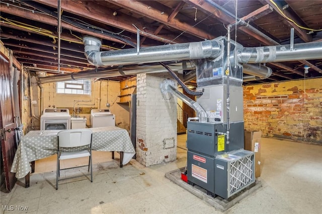 basement featuring washer and clothes dryer, heating unit, and brick wall