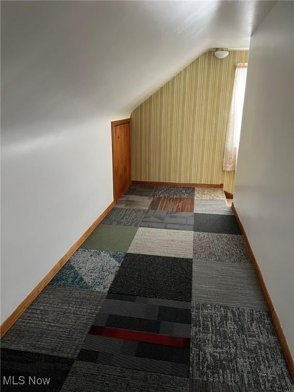 bonus room featuring lofted ceiling and dark colored carpet