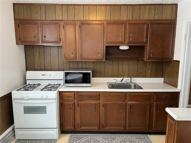 kitchen featuring sink, wooden walls, and white range with gas cooktop