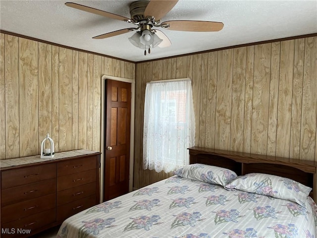 bedroom featuring ceiling fan, crown molding, wood walls, and a textured ceiling