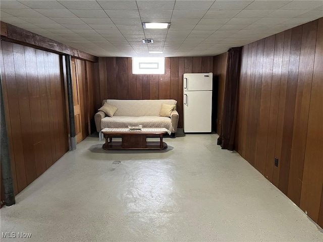 basement featuring white fridge and wood walls