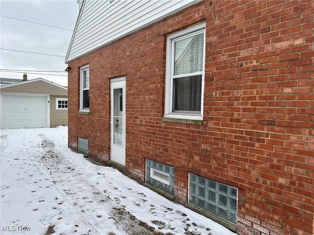 snow covered property with an outbuilding and a garage