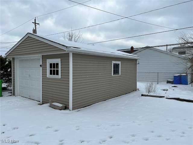 view of snowy exterior featuring a garage and an outbuilding