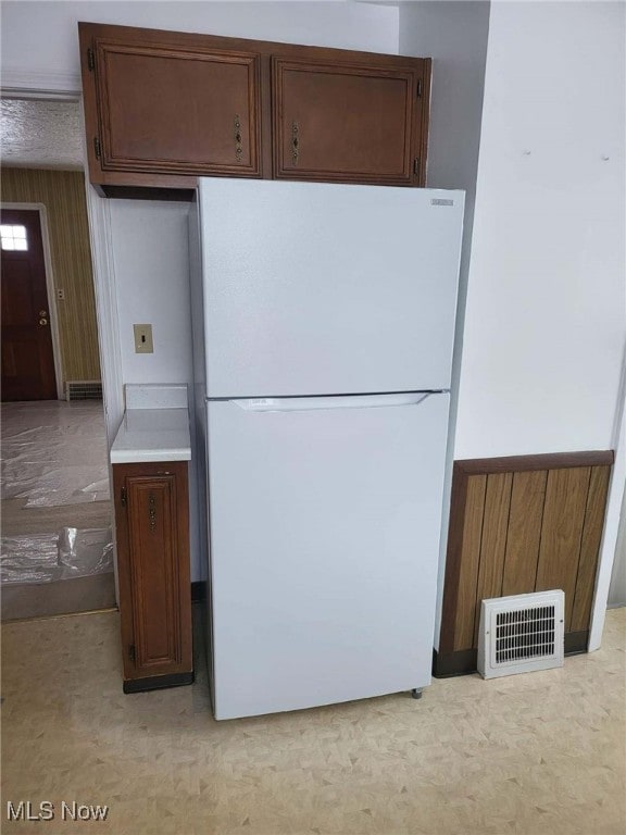 kitchen featuring white refrigerator and wooden walls