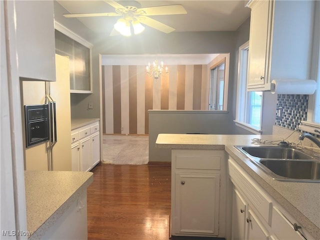 kitchen featuring sink, white cabinetry, white fridge with ice dispenser, and kitchen peninsula