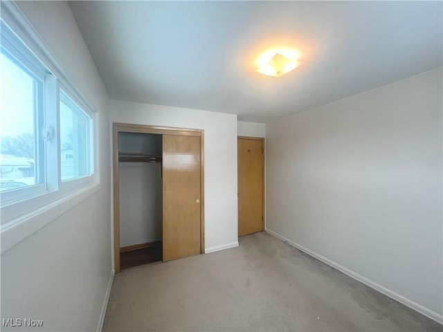 unfurnished bedroom featuring a closet and light colored carpet