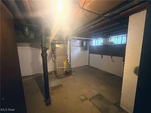 basement featuring electric panel and heating unit