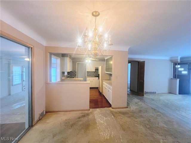 interior space with white fridge, a chandelier, decorative backsplash, white cabinets, and decorative light fixtures