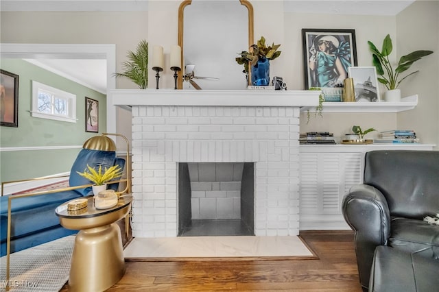 interior details with wood-type flooring, a brick fireplace, and crown molding