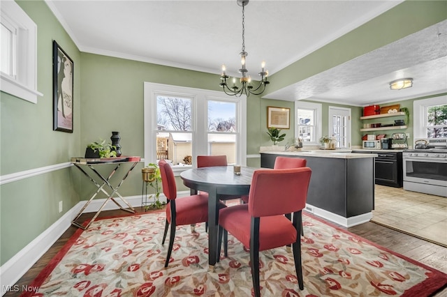 dining space featuring a textured ceiling, light wood-type flooring, crown molding, and a notable chandelier