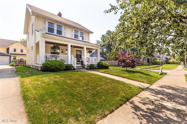 view of front of home featuring covered porch, a garage, and a front yard