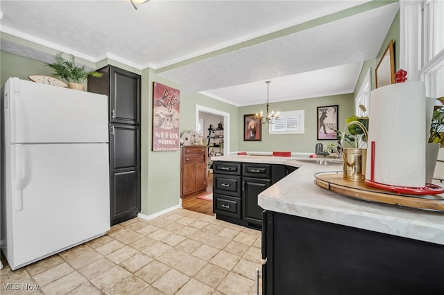 kitchen with crown molding, a notable chandelier, white refrigerator, pendant lighting, and sink