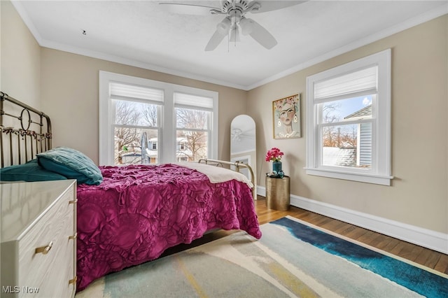 bedroom featuring hardwood / wood-style floors, ceiling fan, crown molding, and multiple windows