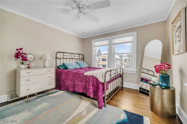 bedroom featuring hardwood / wood-style floors, ceiling fan, and crown molding