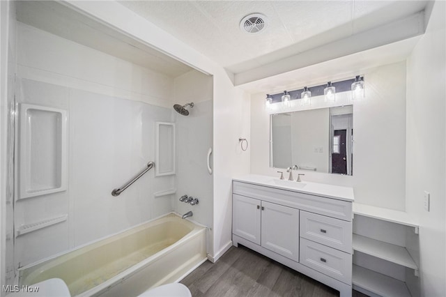 full bathroom featuring a textured ceiling, shower / tub combination, hardwood / wood-style flooring, toilet, and vanity