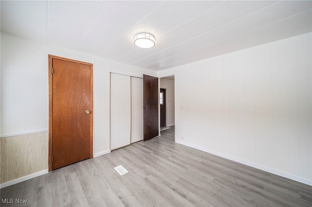 unfurnished bedroom featuring wood walls and light hardwood / wood-style floors