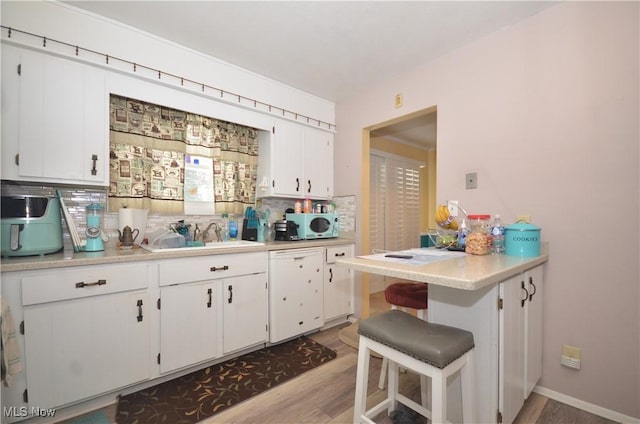 kitchen featuring light hardwood / wood-style floors, white cabinets, a kitchen breakfast bar, and dishwasher