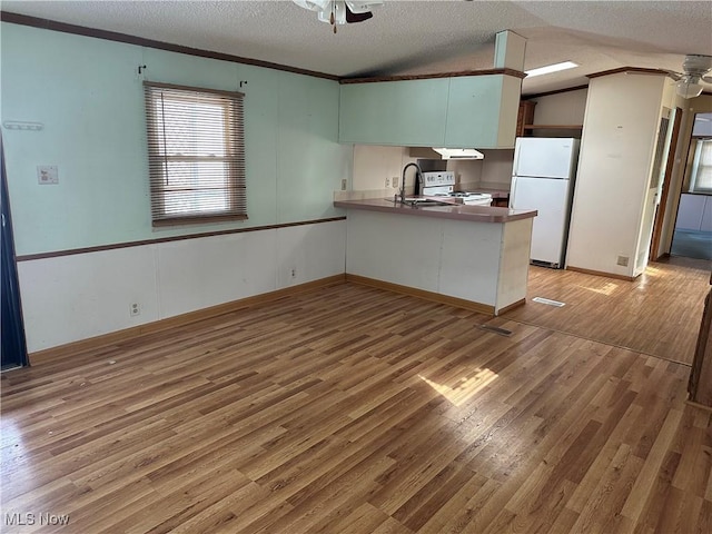 kitchen featuring a textured ceiling, white appliances, ceiling fan, light hardwood / wood-style floors, and kitchen peninsula