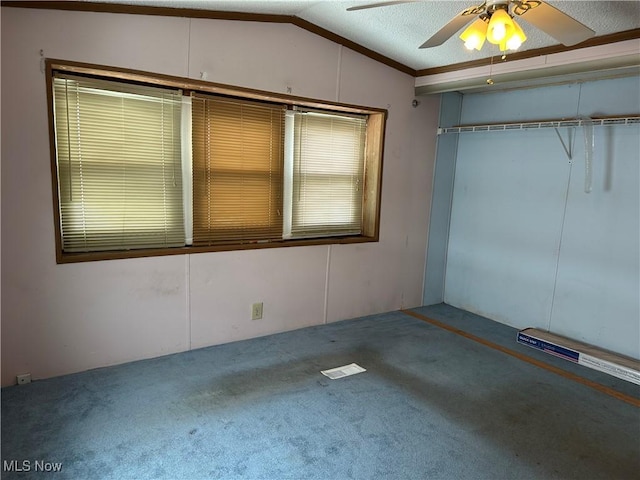 unfurnished bedroom with a textured ceiling, a closet, lofted ceiling, carpet floors, and ceiling fan