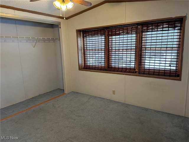 unfurnished bedroom featuring a closet, carpet, ceiling fan, multiple windows, and lofted ceiling