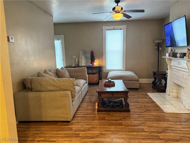 living room featuring a tiled fireplace, ceiling fan, and hardwood / wood-style flooring