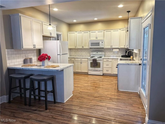 kitchen featuring white appliances, kitchen peninsula, white cabinetry, and hanging light fixtures