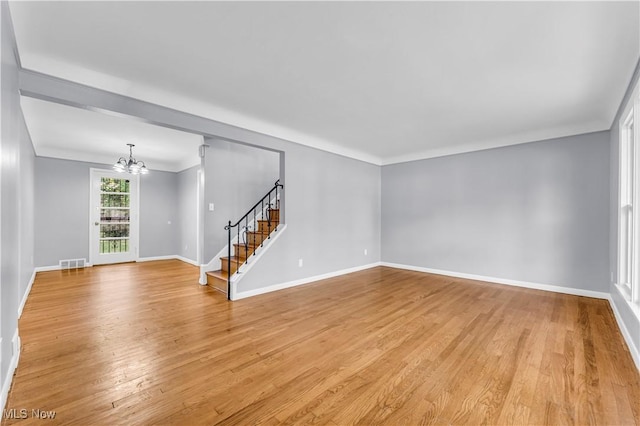 empty room featuring a chandelier and light wood-type flooring