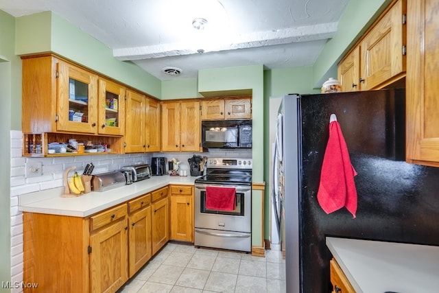 kitchen featuring backsplash, light tile patterned floors, and black appliances