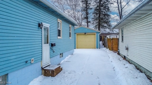 snow covered property featuring a garage and an outdoor structure