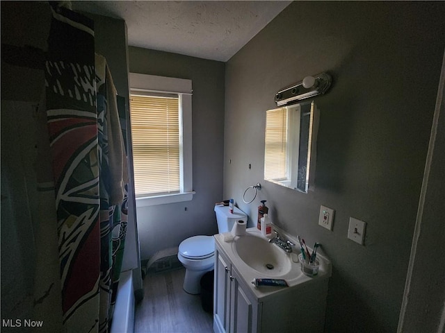 bathroom with a textured ceiling, a shower with shower curtain, hardwood / wood-style flooring, toilet, and vanity