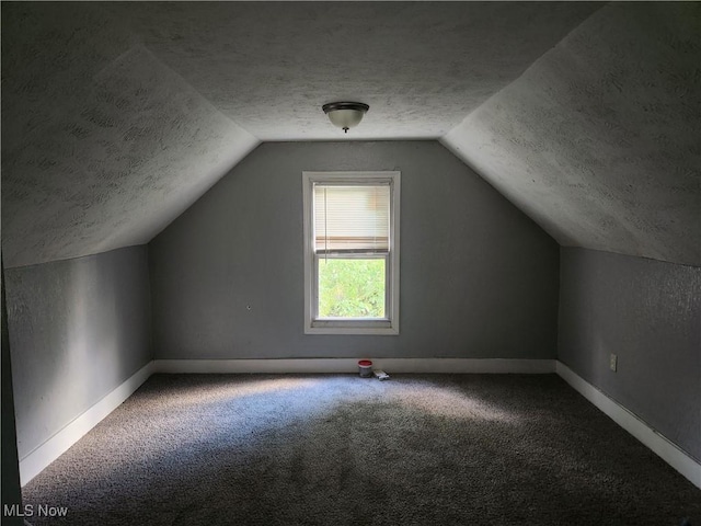 bonus room with a textured ceiling, vaulted ceiling, and carpet flooring