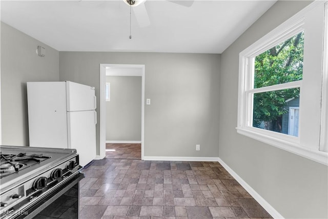 kitchen with white refrigerator, ceiling fan, and black gas stove