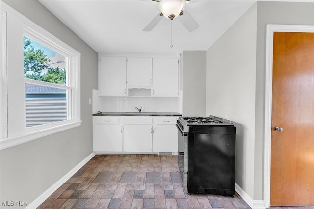 kitchen with sink, white cabinets, ceiling fan, stainless steel gas range oven, and backsplash