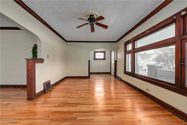 unfurnished room with a textured ceiling, light wood-type flooring, ceiling fan, and crown molding