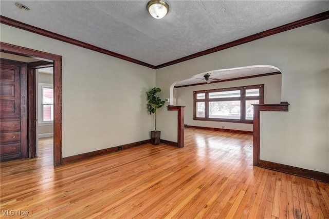 spare room with a textured ceiling, ceiling fan, light wood-type flooring, and plenty of natural light