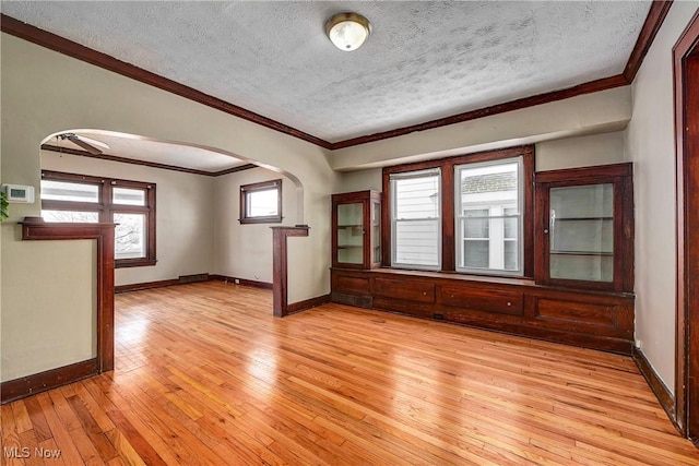 spare room featuring a textured ceiling, ceiling fan, light wood-type flooring, and ornamental molding