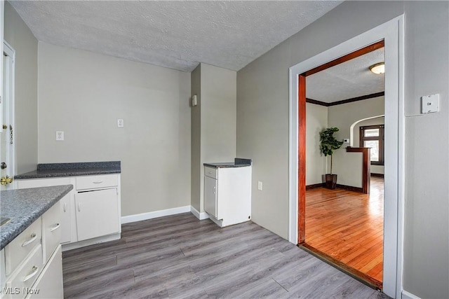 kitchen featuring white cabinets, a textured ceiling, and wood-type flooring