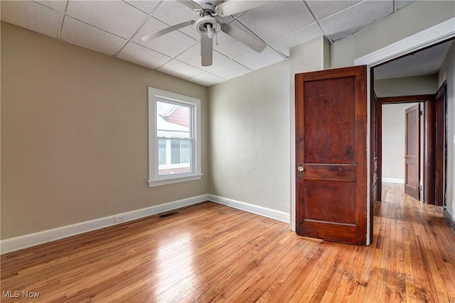 unfurnished room featuring a drop ceiling, light wood-type flooring, and ceiling fan