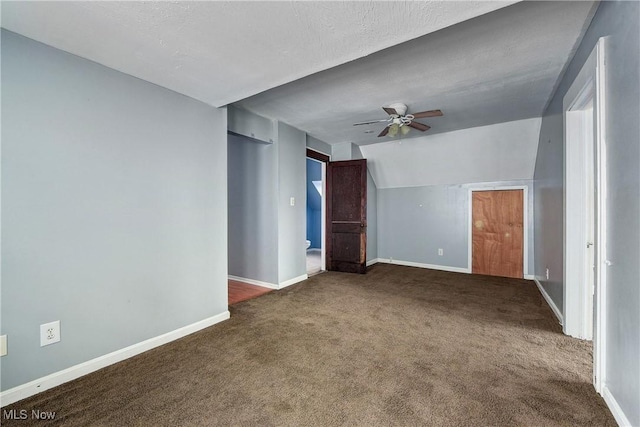 carpeted empty room with ceiling fan, lofted ceiling, and a textured ceiling