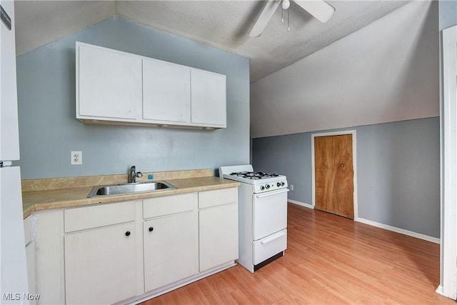 kitchen with sink, white cabinets, lofted ceiling, white gas range oven, and light hardwood / wood-style flooring