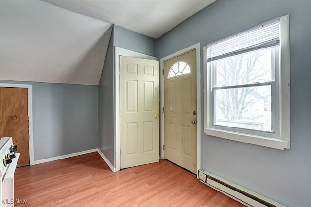 foyer entrance with vaulted ceiling, a baseboard heating unit, and light hardwood / wood-style floors