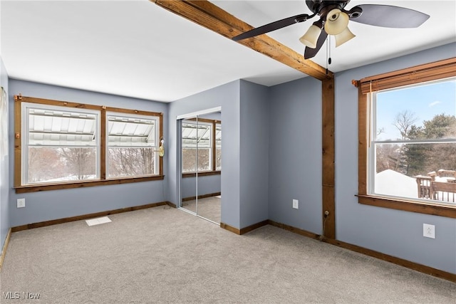 unfurnished bedroom with light carpet, ceiling fan, a closet, and multiple windows