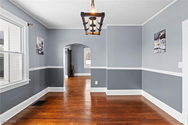 unfurnished dining area featuring dark hardwood / wood-style flooring, an inviting chandelier, and ornamental molding