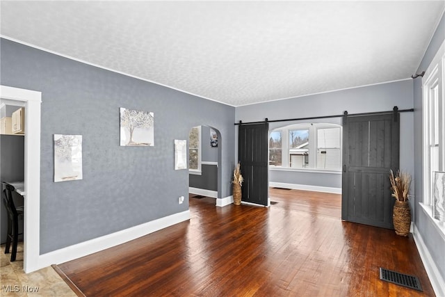 living room featuring a textured ceiling, a barn door, and dark hardwood / wood-style floors