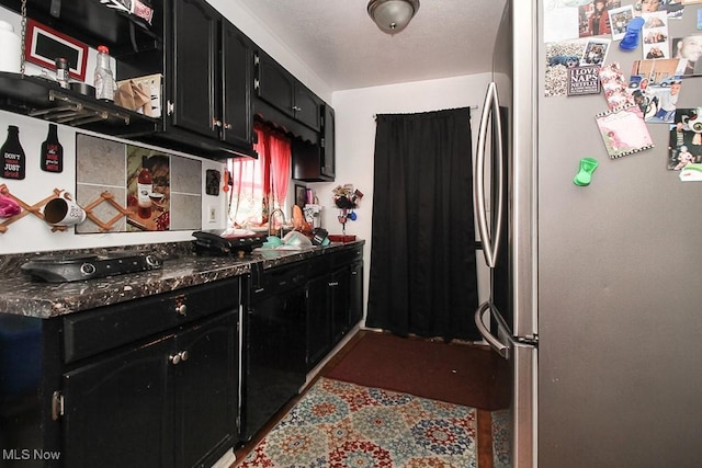 kitchen with sink, stainless steel fridge, dark stone countertops, and decorative backsplash