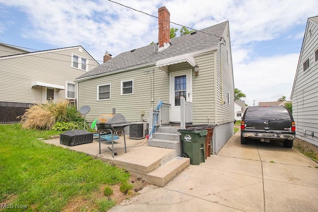 rear view of property featuring cooling unit, a patio area, and a yard