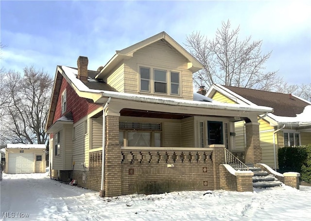 view of front of property featuring a garage, covered porch, and an outbuilding