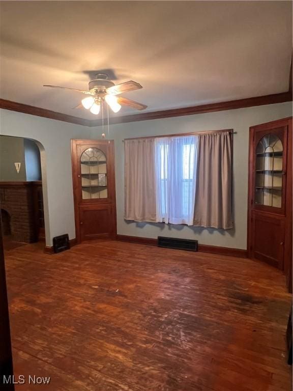 unfurnished room featuring ceiling fan, crown molding, dark hardwood / wood-style floors, and a fireplace