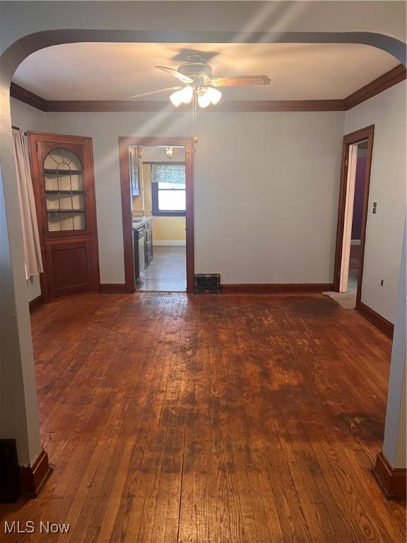 empty room with ceiling fan, dark hardwood / wood-style flooring, and ornamental molding