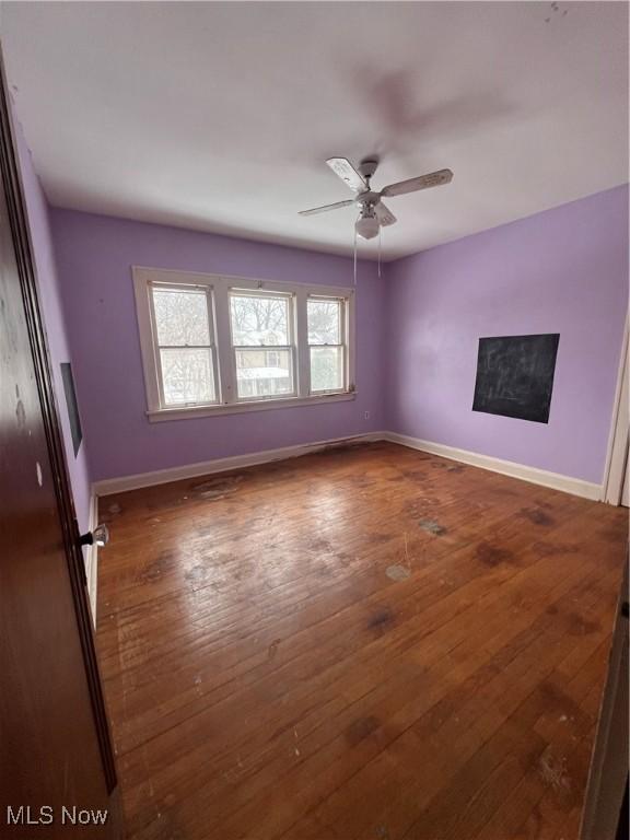 empty room with ceiling fan and dark hardwood / wood-style flooring